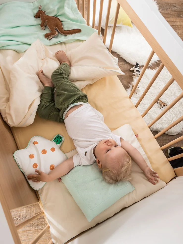 Małe dziecko leżące wygodnie na materacu w łóżeczku